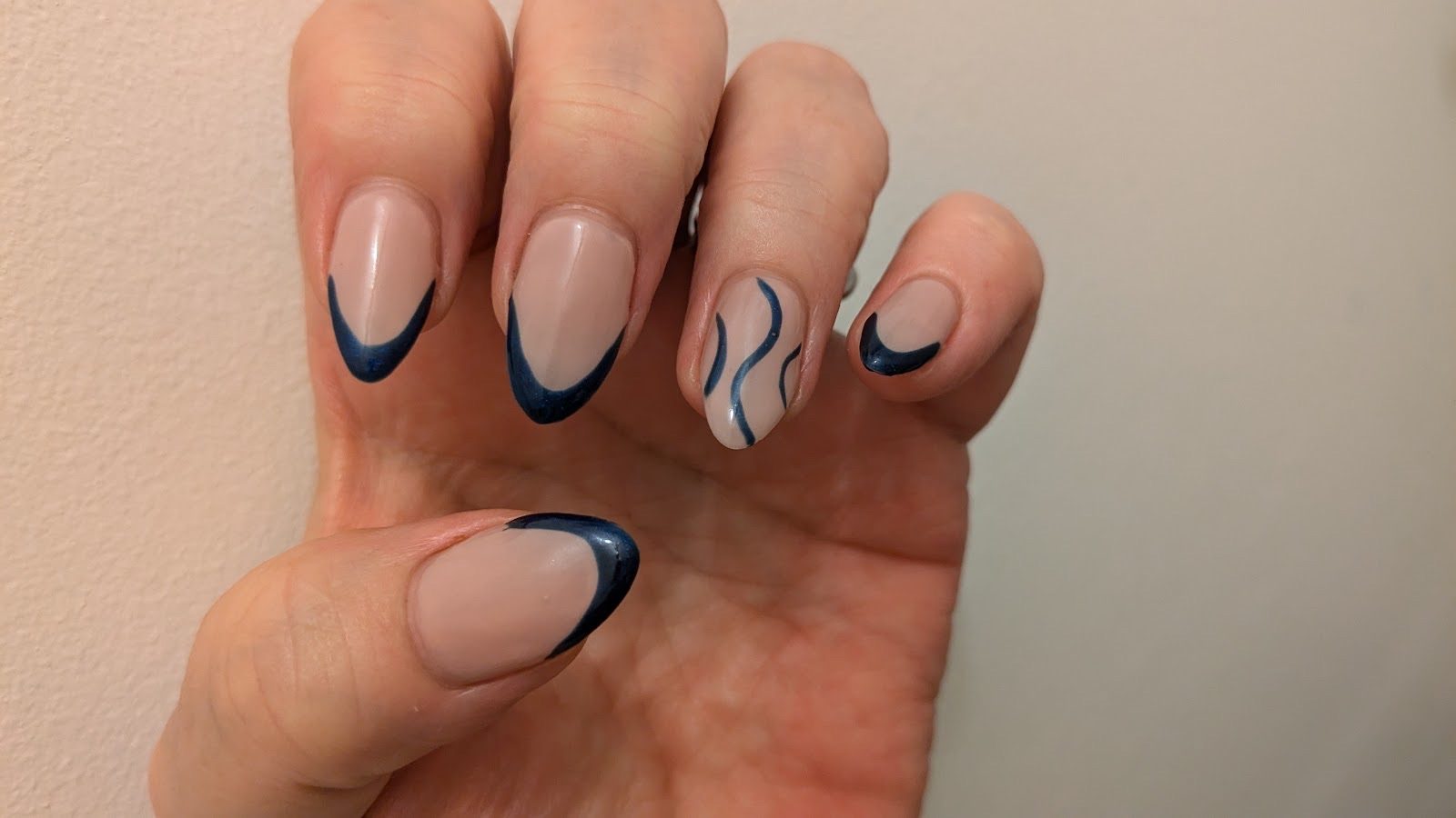 Almond nails with navy and white abstract swirl and side-French line art on a nude base