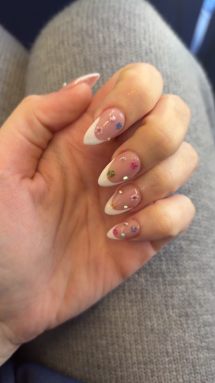 Long almond nude nails with delicate hand-painted floral and gold-fleck art
