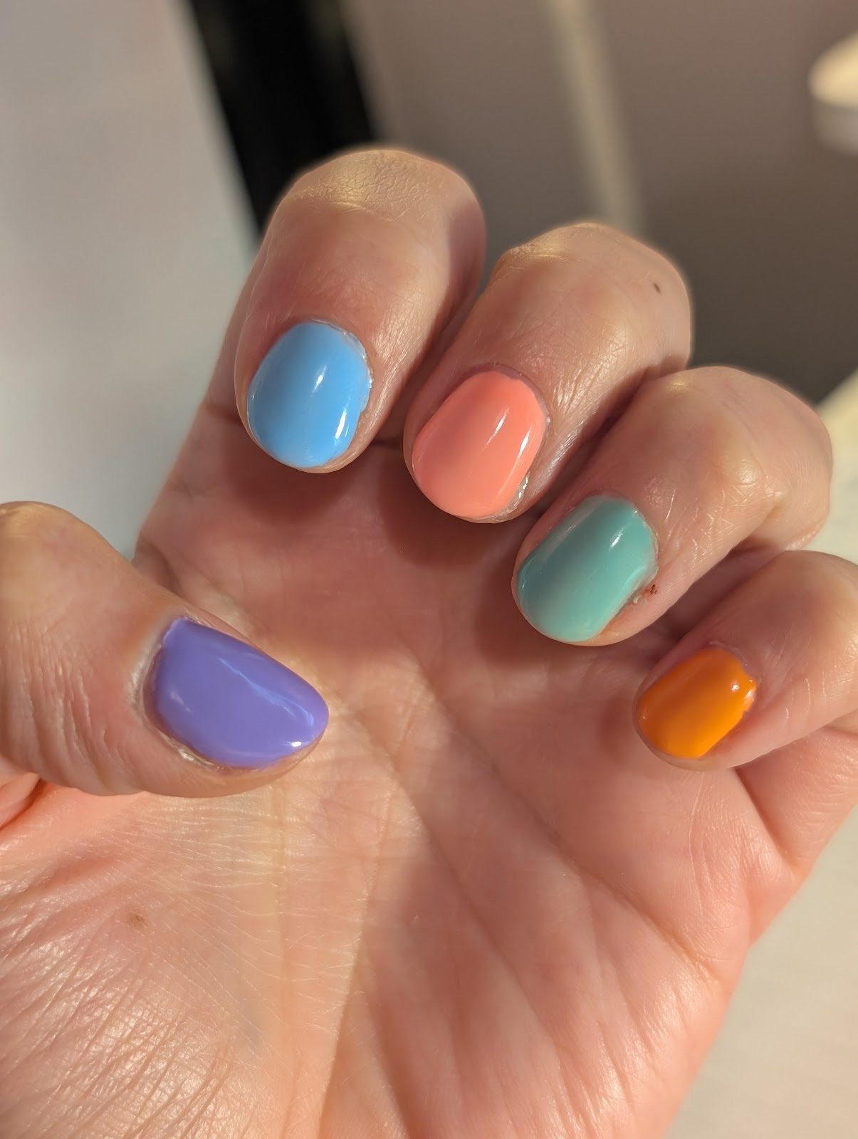 Short glossy nails in a bright mismatched set of blue, coral, mint, orange and purple